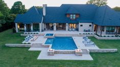 an aerial view of a house with a swimming pool and patio area in the foreground