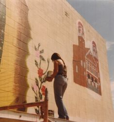 a woman is painting a mural on the side of a building