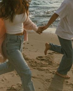 two people holding hands while walking on the beach