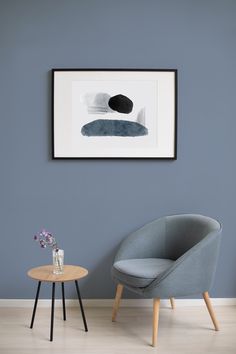 a chair and table in front of a blue wall with a painting on the wall