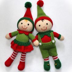 two knitted dolls are laying next to each other on a white surface, one is green and the other is red