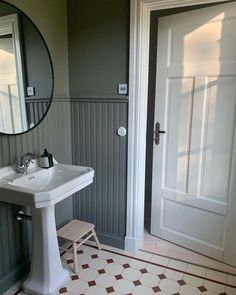 a white sink sitting under a bathroom mirror next to a wooden door in a bathroom