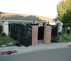 two doors are being installed in front of a house that has been covered with black tarp