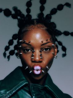 a woman with piercings on her face and nose is wearing a green leather jacket