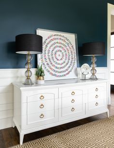 two lamps are sitting on top of a white dresser in a room with blue walls