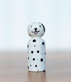 a white and black dog figurine sitting on top of a wooden table