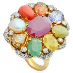 A simple 18K gold ring in the form of oval shape set with the nine planetary gems (navratna) and full cut diamonds. Starting with blue sapphire at the lower end, the nine gemstones include a coral, yellow sapphire, emerald, cat's eye, cultured pearl, hessonite garnet, blue sapphire and a natural ruby at centre. The concept of navratna is born at the core of Indian hindu culture, to attain the maximum prophylactic powers of the nine gems, the gems need to be set with open-back mounts so that light passed through the stones transmitting their energies to the body. The ring embodies nearly 11.50gms of fine gold and 14.21cts of natural stones accompanied with 0.60cts diamonds. Navratna Ring, Hindu Culture, Multi Sapphire, Hessonite Garnet, 18k Gold Ring, Modern Ring, Uncut Diamond, Precious Gems, Yellow Sapphire