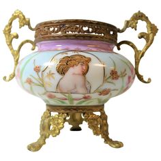 an ornate vase with a female figure painted on the side and gold trimmings