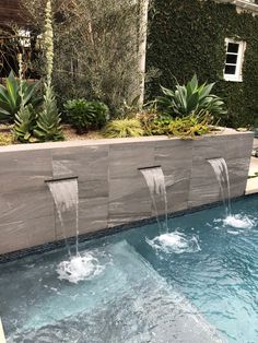 an outdoor fountain with water running down it's sides and plants growing on the side