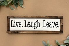 a sign that says live laugh leave on the side of a wall next to plants