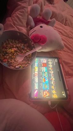 a stuffed cow eating cereal from a bowl next to a cell phone on a bed