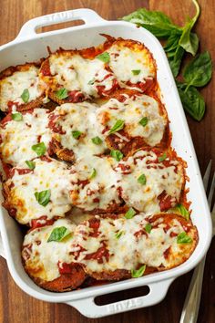 a casserole dish with meat, cheese and spinach on the side next to a fork