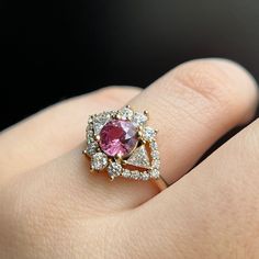 Similar to our blue sapphire version, this pink beauty features a 1.49ct pink sapphire surrounded by sparkly white diamonds. She's the perfect art-deco inspired engagement ring for someone who is into a nontraditional engagement look. Please note resizing this ring adds an extra 7-10 days for delivery. Pink Brilliant Cut Moissanite Diamond Ring, Pink Moissanite Diamond Ring With Brilliant Cut, Pink Sapphire Ring With Brilliant Cut Diamond, Dazzling Pink Diamond Ring With Accent Stones, Pink Pear-shaped Rose Cut Diamond Jewelry, Elegant Pink Trillion-cut Jewelry, Pink Marquise Cut Diamond Ring, Pink Diamond Ring With Accent Stones, Pink Sapphire Ring With Diamond Accents Round Cut