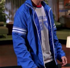 the young man is wearing a blue jacket and standing in front of a television set