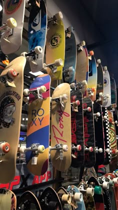 many skateboards are lined up on display in a room with other boards hanging from the ceiling