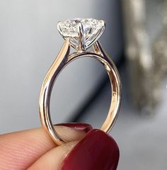 a close up of a person's hand holding an engagement ring