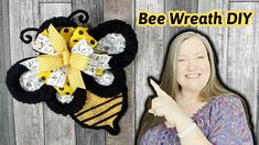 a woman pointing at a bee wreath with the words bee wreath diy on it