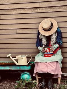 a woman sitting on a bench next to a wheelbarrow with a watering can