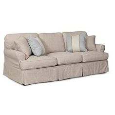 a beige couch with blue and white pillows on it's back end, sitting in front of a white background