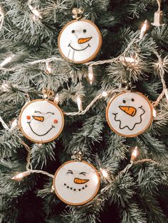 three snowman ornaments hanging from a christmas tree