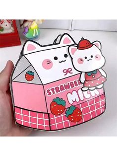 a person holding up a pink box with a cat on it and strawberries in the background