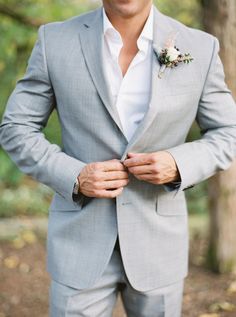 a man in a gray suit and flower boutonniere is posing for the camera