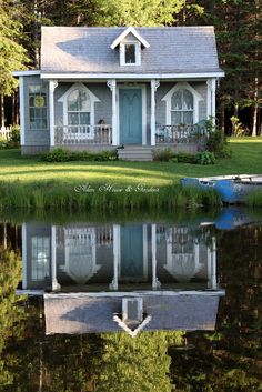 a house sitting on top of a lush green field next to a lake