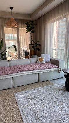 a living room filled with furniture next to a window covered in curtains and rugs