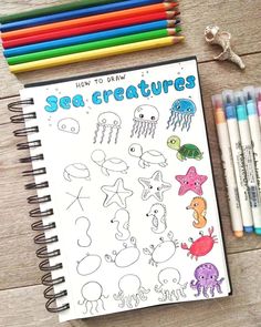 a notebook with sea creatures drawn on it next to colored pencils and crayons