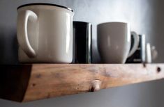 coffee mugs are lined up on a shelf