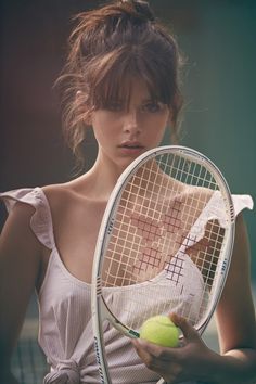 a woman holding a tennis racket and ball