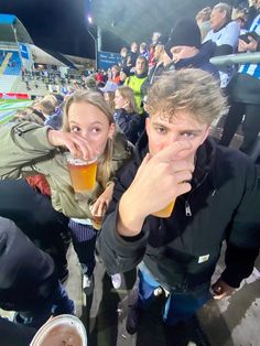 a man and woman drinking beer at a sporting event