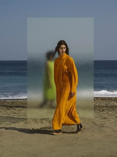 a woman standing on top of a sandy beach next to the ocean in an orange dress