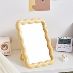 a mirror sitting on top of a white table next to a clock and alarm clock