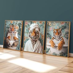 three framed paintings of tigers sitting in front of a wall with blue walls and wooden floors