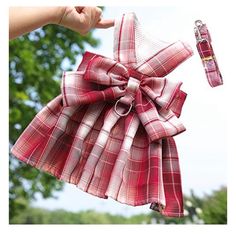 a red and white plaid dress hanging on a clothes line with a hand holding it