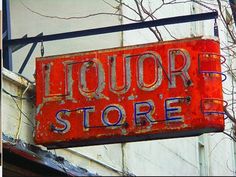 an old neon sign hanging from the side of a building that says, liquor store