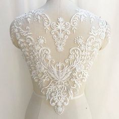 the back of a wedding dress with white lace on it and an open neckline