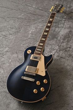 an electric guitar sitting on top of a gray floor next to a black and white wall