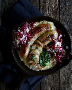 a bowl filled with meat and veggies on top of a wooden table next to a fork