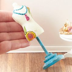 a hand holding a blue toothbrush in front of a white wall and wooden floor