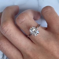 a woman's hand with a diamond ring on top of her finger, showing the center stone