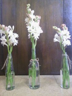 three clear vases with white flowers in them