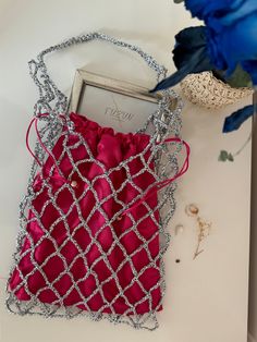 a red purse sitting on top of a table next to a blue flower and an empty box