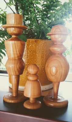 three wooden candlesticks sitting next to a potted plant