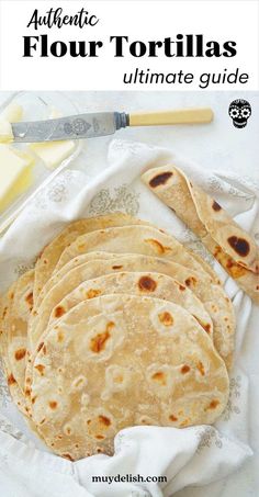 four homemade flour tortillas sitting on top of a white cloth next to butter