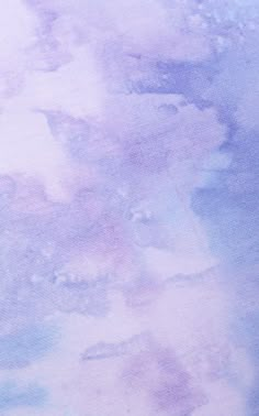 an airplane is flying in the sky over some watercolor paint on paper that looks like it has been dyed purple and blue