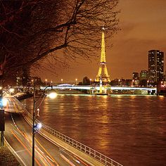 the eiffel tower is lit up at night over the river seine in paris