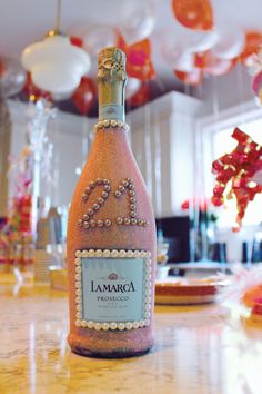 a bottle of champagne sitting on top of a counter next to plates and balloons in the background