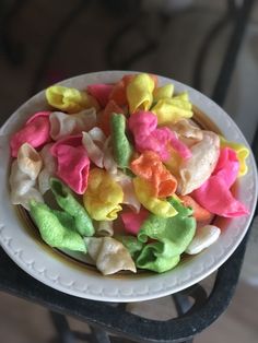 a white plate topped with colorful candies on top of a wooden table next to a black chair